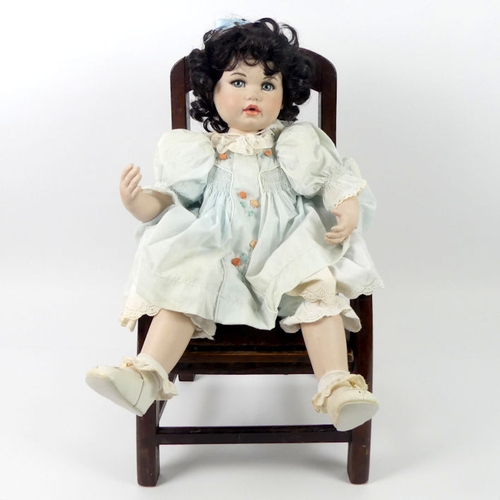 318 - A modern bisque doll, sitting in a chair, 54cm.