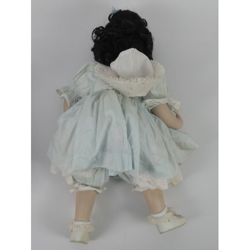 318 - A modern bisque doll, sitting in a chair, 54cm.