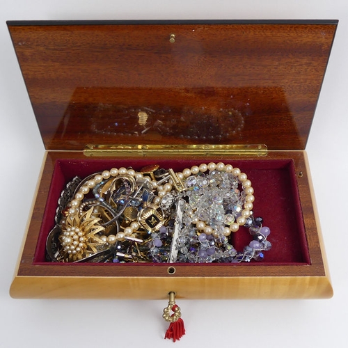 50 - A musical jewellery box of mixed costume jewellery, including two silver bangles.