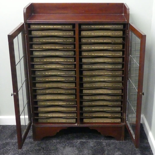 499 - A mahogany fitted bookcase holding thirty-two volumes of Encyclopaedia Britannica with suede covers,... 