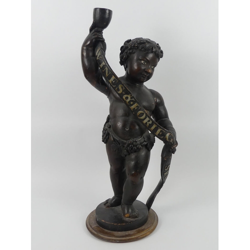 241 - A carved wooden advertising figure of Bacchus, holding a goblet and banner, which reads wines and fo... 