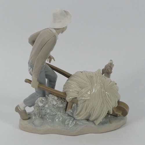 316 - A Lladro figure of a boy with a loaded wheelbarrow and dog, 24 cm x 20 cm.