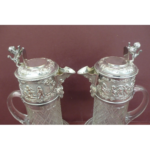 266 - Good pair of silver plated cut glass claret jugs having lion rampant and shield thumb clasps, cherub... 