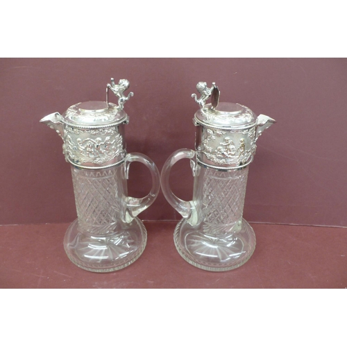 266 - Good pair of silver plated cut glass claret jugs having lion rampant and shield thumb clasps, cherub... 