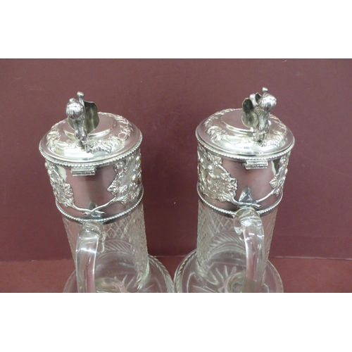 266 - Good pair of silver plated cut glass claret jugs having lion rampant and shield thumb clasps, cherub... 