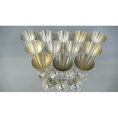 58 - A dozen Stuart Devlin parcel gilt silver champagne goblets with conical tops bark stems and circular... 