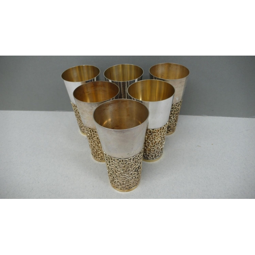 61 - A set of six Stuart Devlin parcel gilt silver beakers with blind fretwork decoration to lower half o... 