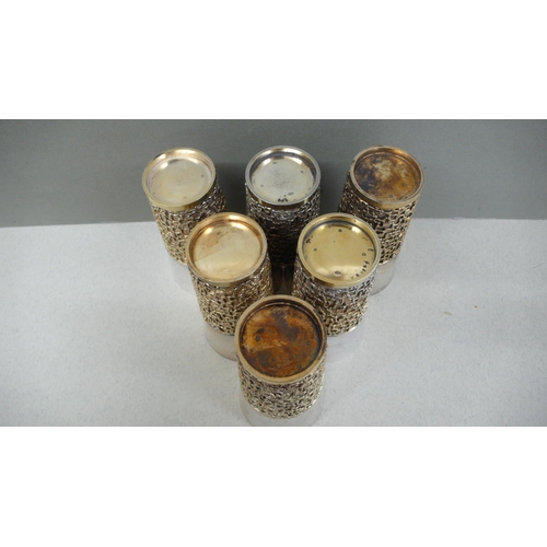 61 - A set of six Stuart Devlin parcel gilt silver beakers with blind fretwork decoration to lower half o... 