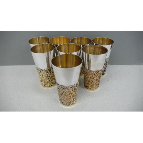 63 - A set of eight Stuart Devlin parcel gilt silver beakers with blind fretwork decoration to lower half... 