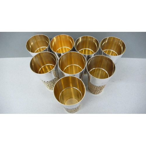 63 - A set of eight Stuart Devlin parcel gilt silver beakers with blind fretwork decoration to lower half... 