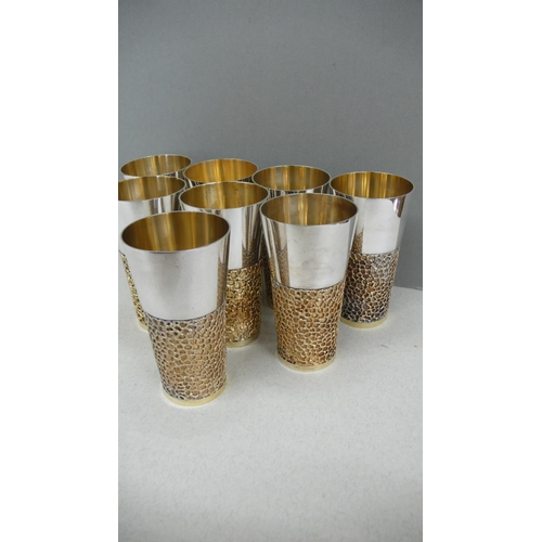 63 - A set of eight Stuart Devlin parcel gilt silver beakers with blind fretwork decoration to lower half... 