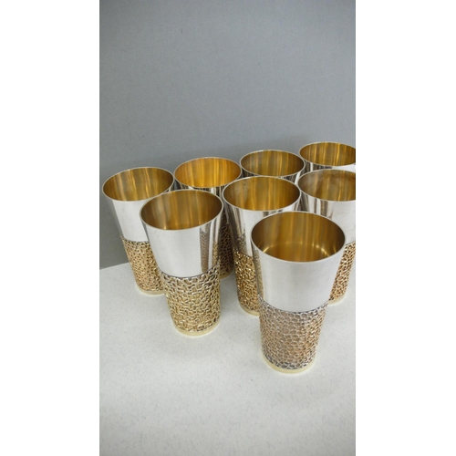 63 - A set of eight Stuart Devlin parcel gilt silver beakers with blind fretwork decoration to lower half... 