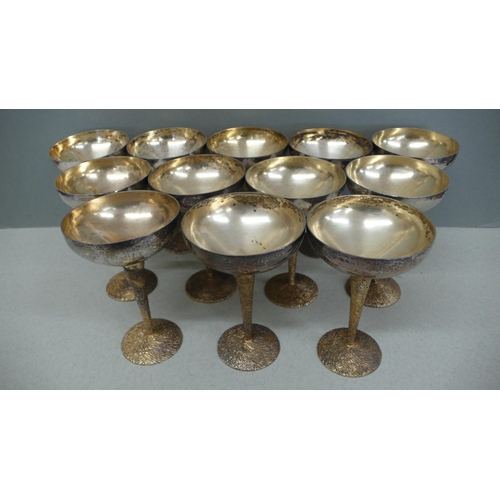 64 - A set of twelve Stuart Devlin parcel Gilt silver cocktail goblets with hammered bowls, twist bark de... 