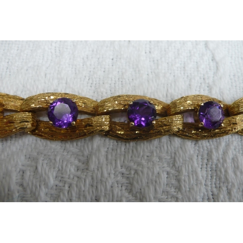 371 - A good 18 ct. gold amethyst bracelet with bark finish and 15 cts. of amethysts each dtone diam 8mm -... 