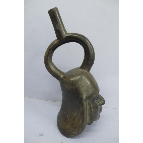 131 - An Early/Middle period blackware pottery Stirrup Vessel in the form of a mans head wearing a headdre... 