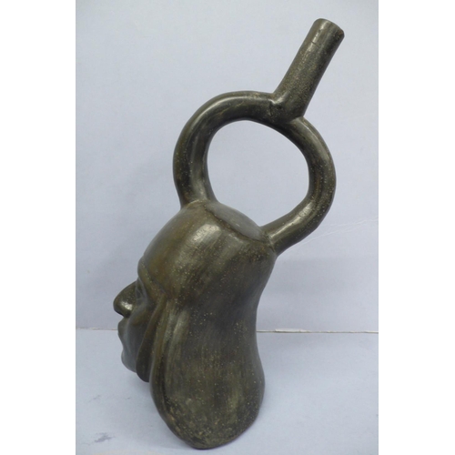 131 - An Early/Middle period blackware pottery Stirrup Vessel in the form of a mans head wearing a headdre... 