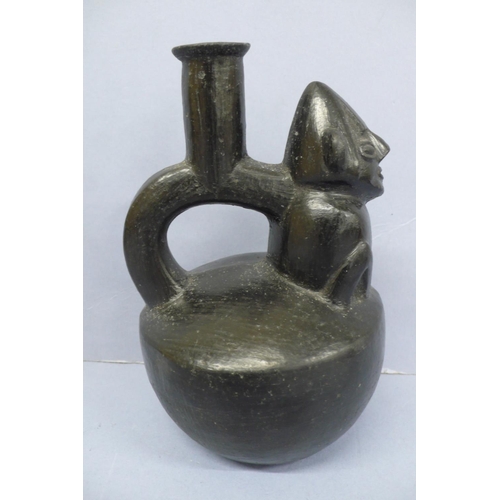 134 - A Vicus Blackware Pottery Effigy Stirrup Handle Vessel in the form of a restrained man in a conical ... 