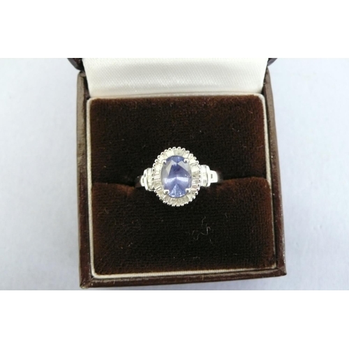 174 - A Platinum Ring set with oval Ceylon Sapphire surrounded by baguette cut diamonds, Size L/M