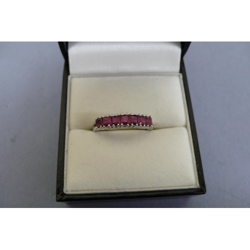 180 - 18ct white gold ruby ring set with seven square stones. Size M