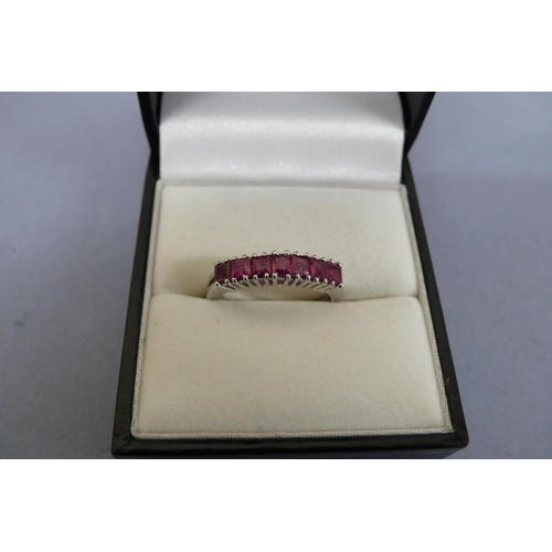 180 - 18ct white gold ruby ring set with seven square stones. Size M