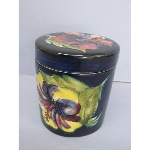 21 - Moorcroft Jar with cover having floral decoration to lid and body on a dark blue ground, marked 'Mad... 