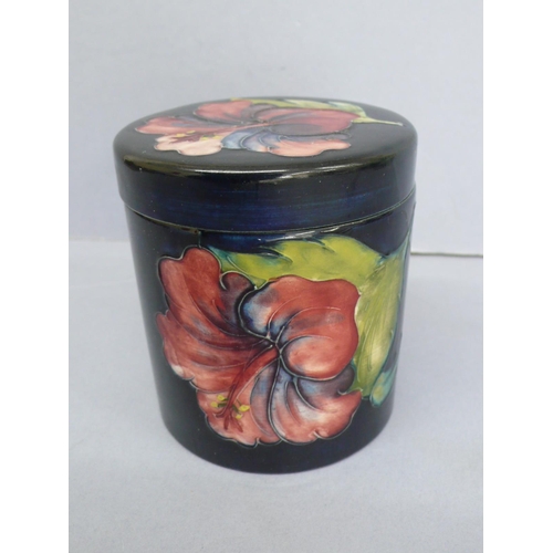 21 - Moorcroft Jar with cover having floral decoration to lid and body on a dark blue ground, marked 'Mad... 