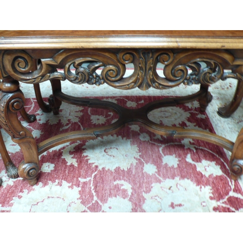 52 - A walnut carved occasional table with X stretcher on carved cabriole legs - width 28 ins approx