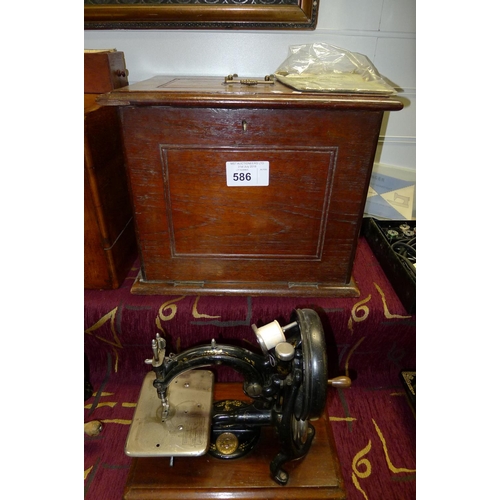 586 - A decorative antique hand cranked sewing machine by Willcox and Gibbs with a wooden carry case