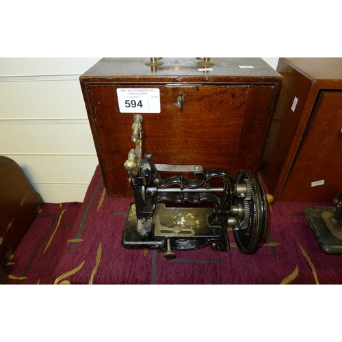 594 - A small decorative antique hand crank sewing machine by Weir in a wooden carrying case