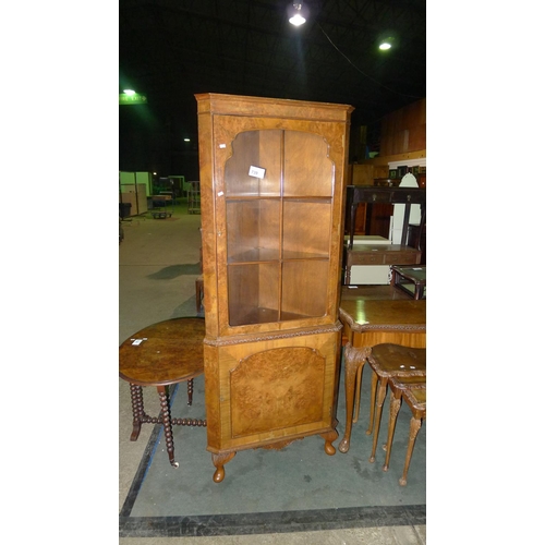 739 - A reproduction walnut floor standing corner cabinet with a glazed door enclosing shelves and a panel... 