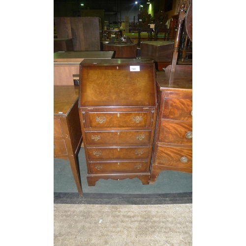 749 - A small walnut bureau with a fall front enclosing a fitted interior and four drawers under