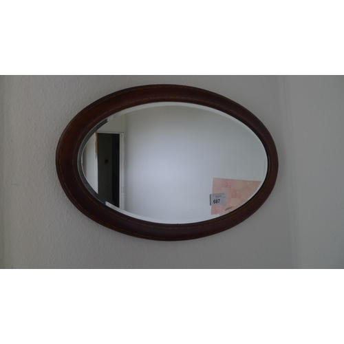 687 - An oval bevelled wall mirror in an inlaid mahogany frame