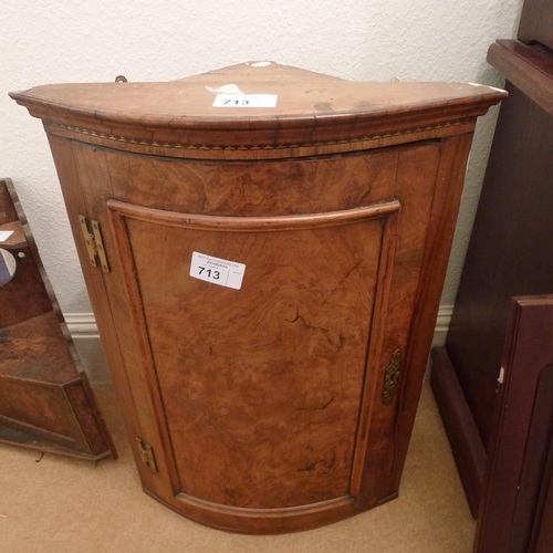 713 - A bow front walnut wall hanging corner cabinet with a panelled door