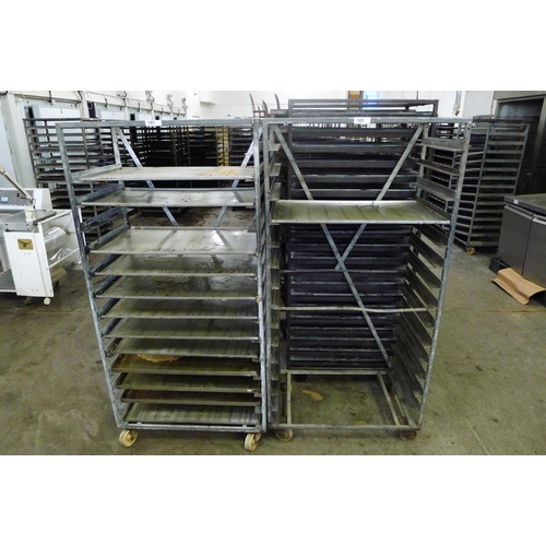 185 - 2 metal wheeled bakers racks - 1 containing a quantity of metal trays and the is empty but trays wil... 