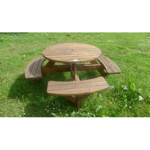 A wooden, round, garden/patio table with 4 fitted benches