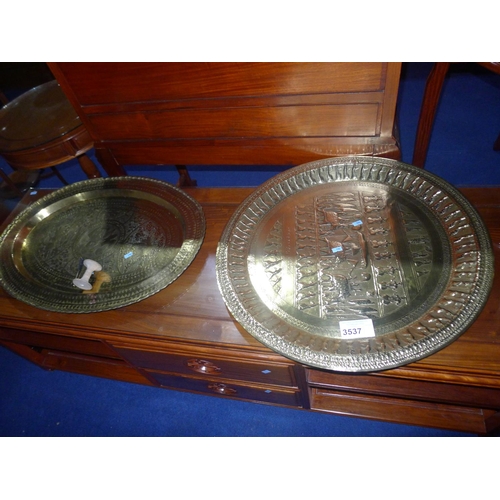 3537 - An oval oriental engraved brass tray and a circular embossed brass tray