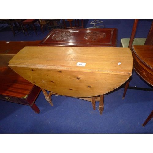 3550 - A circular topped pine gateleg table on turned supports