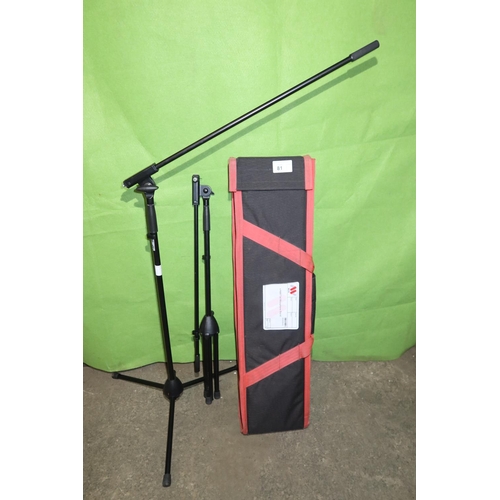 81 - 2 tall black metal folding tripod microphone stands by K & M supplied with a soft carry / storage ba... 