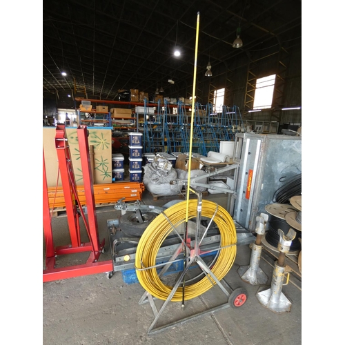 595 - A yellow fibreglass duct rodder / cable puller on a floor standing metal reel (length unknown)