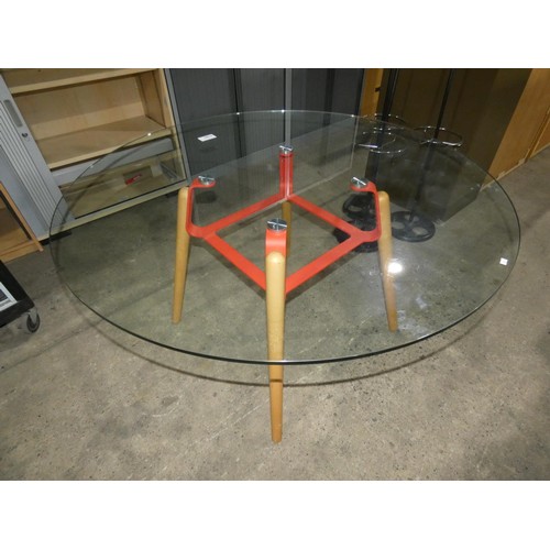 1190 - A round glass table with red metal frame on wooden legs approx 130cm