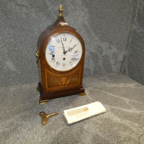 2815 - A traditional style domed top bracket clock with side ring handles, a top brass finial and an inlaid... 