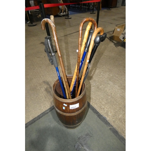 2957 - A copper bound oak barrel stick stand with a selection of walking sticks