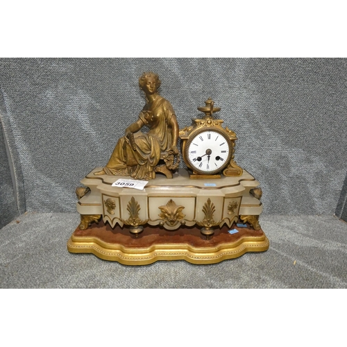 3059 - A decorative alabaster based clock with ornate ormolu and gilt decoration surmounted by a seated lad... 