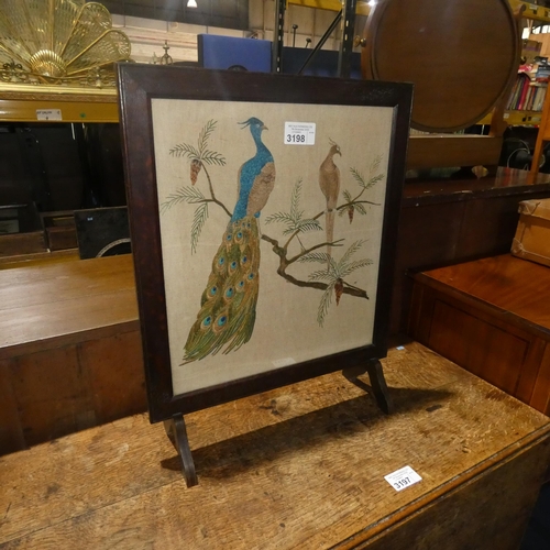 3198 - An oak framed firescreen with embroidered peacock decoration