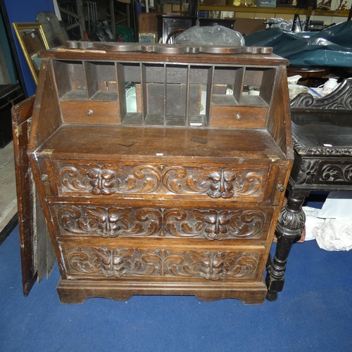 3120 - A heavily carved dark oak Bureau with a fall front enclosing a fitted interior and 3 drawers under, ... 