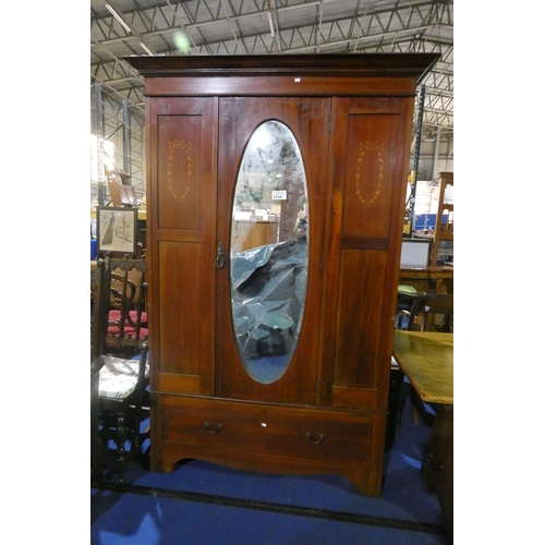 3154 - An Edwardian inlaid mahogany wardrobe with an oval bevelled mirrored door and a drawer under, approx... 