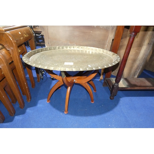 3216 - An oval engraved brass tray table with wooden legs