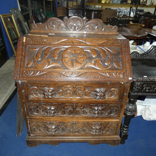 3120 - A heavily carved dark oak Bureau with a fall front enclosing a fitted interior and 3 drawers under, ... 