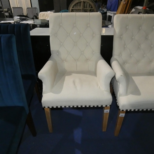 A light upholstered button back dining chair with light wood legs