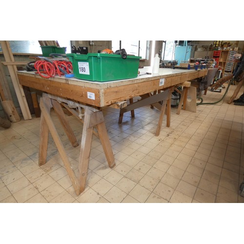 181 - A large flat work table sitting on three trestle supports, approx 305 x 122 x 96cm high